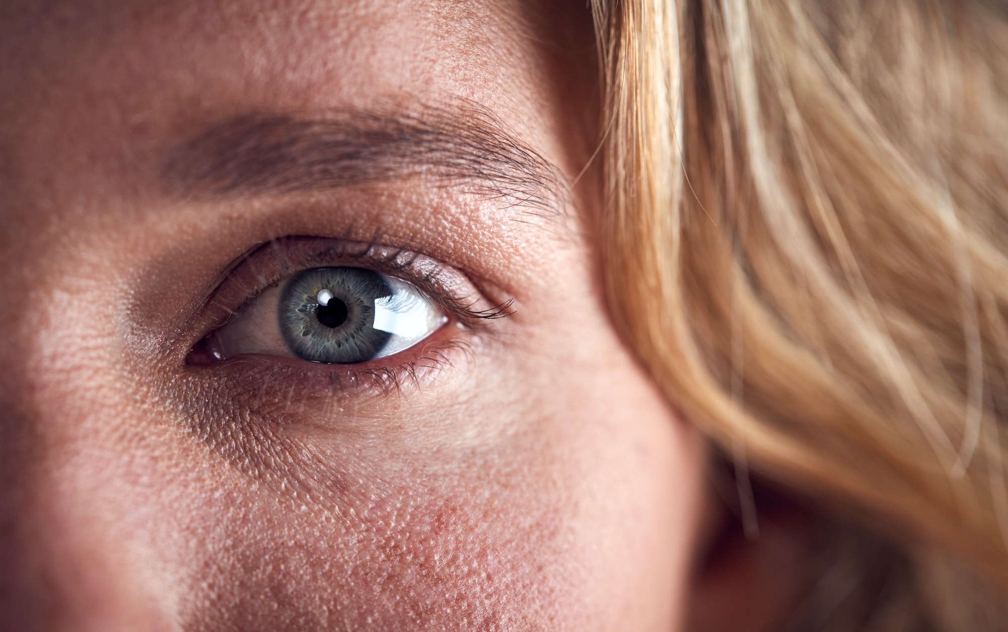 Close Up Of Eye Of Woman Looking Scared Against Black Studio Background